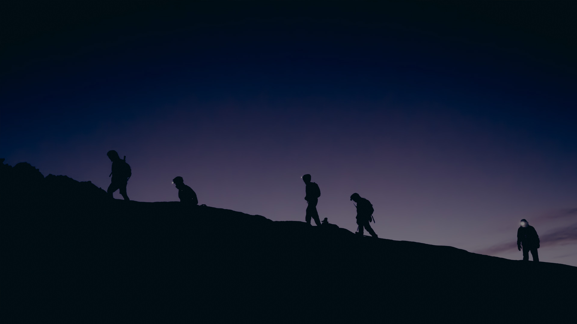 Silhouette of people trekking up a mountain